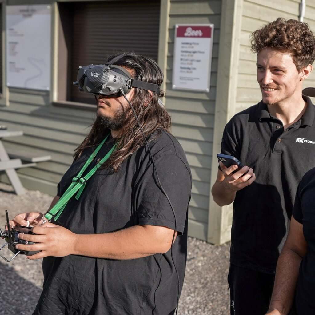 FX Productions Canada A person wearing FPV goggles operates a drone controller while another stands beside them holding a smartphone, both outdoors near a building—capturing creative moments for FX Productions Canada, a leading Toronto Video Production company. Toronto Video Production Company
