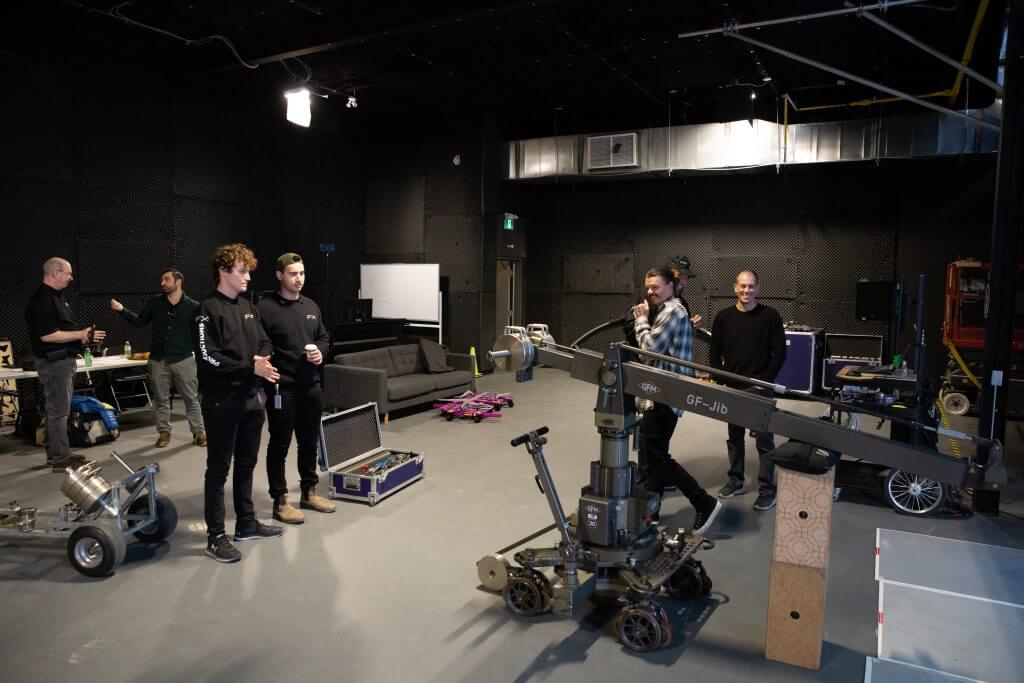 FX Productions Canada A group of people stand and talk in a spacious, well-lit studio with film equipment, a camera crane, and set pieces scattered around at FX Productions Canada, a leading Toronto Video Production company. Toronto Video Production Company