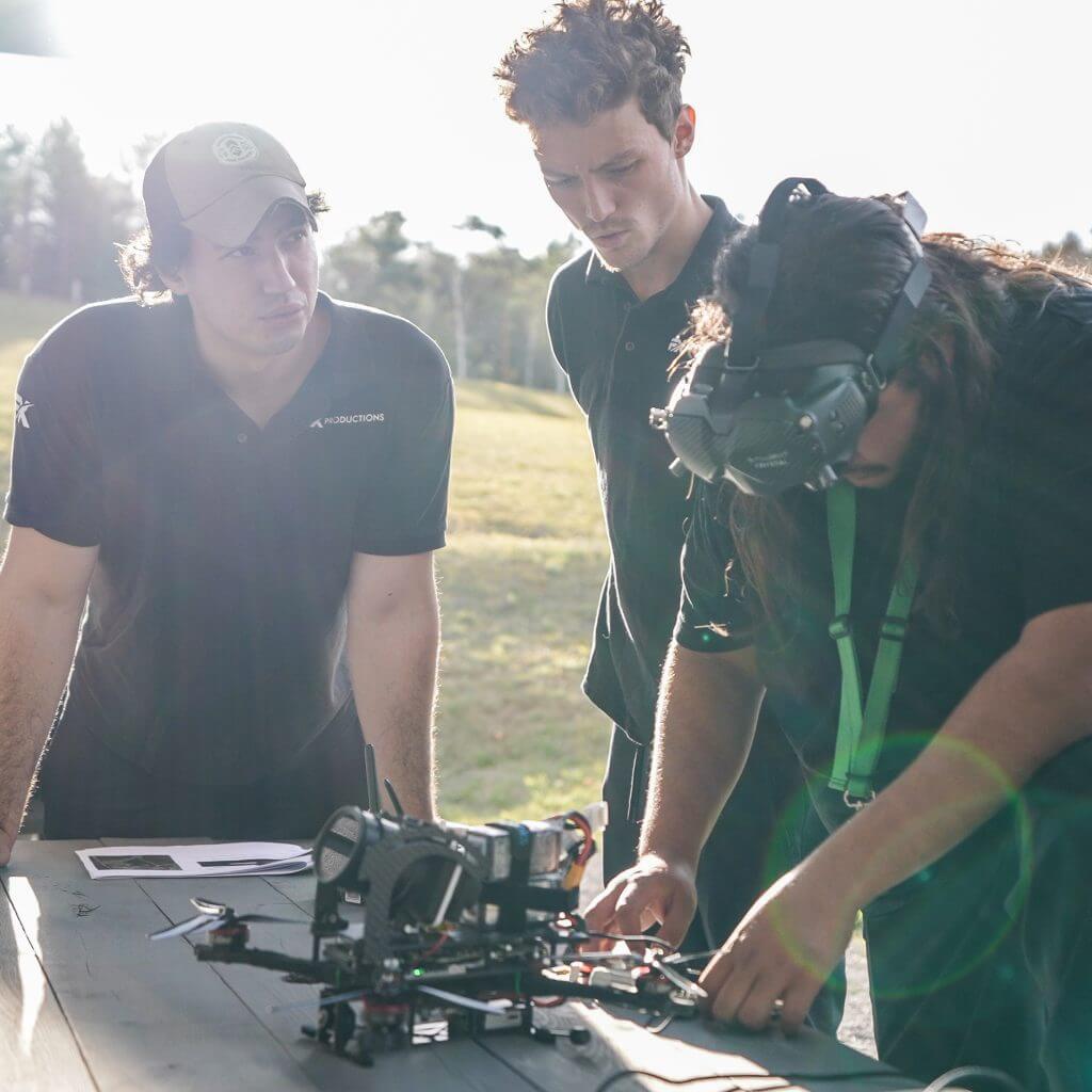 FX Productions Canada Three people inspect a drone on a table outdoors; one wears a VR headset, while the others watch attentively, showcasing innovation from a leading Toronto Video Production company. Toronto Video Production Company