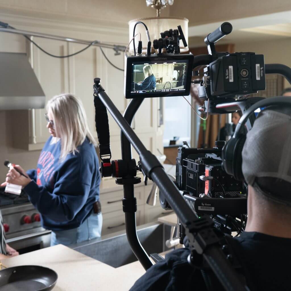 FX Productions Canada A camera crew from a Toronto Video Production company films a woman cooking in a kitchen, with the camera operator capturing her actions on a monitor. Toronto Video Production Company