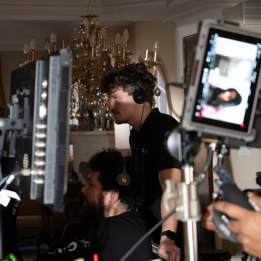 FX Productions Canada Two people wearing headsets monitor screens and filming equipment on a set for FX Productions Canada, with a chandelier and ornate decor in the background—a glimpse into professional Toronto Video Production. Toronto Video Production Company