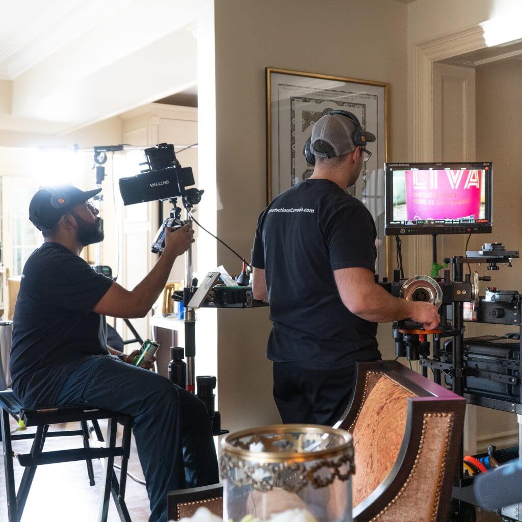 FX Productions Canada Two crew members from FX Productions Canada operate filming equipment and monitor a screen on a film set inside a well-lit room, with various Toronto Video Production gear visible. Toronto Video Production Company