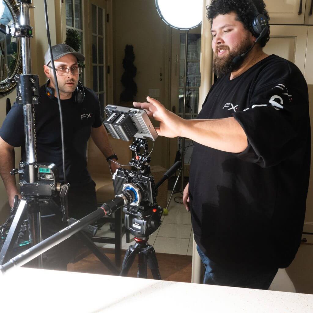 FX Productions Canada Two men wearing headsets stand next to professional video camera equipment indoors, reviewing footage on a monitor for Toronto Video Production. Toronto Video Production Company
