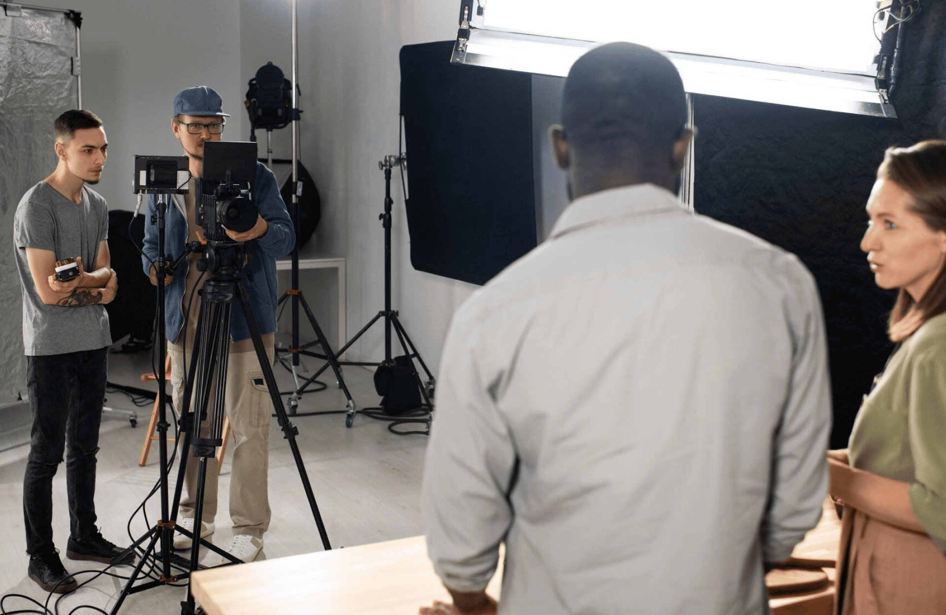 FX Productions Canada A film crew with cameras and lights from FX Productions Canada records two people standing and talking at a table in a studio setting. Toronto Video Production Company
