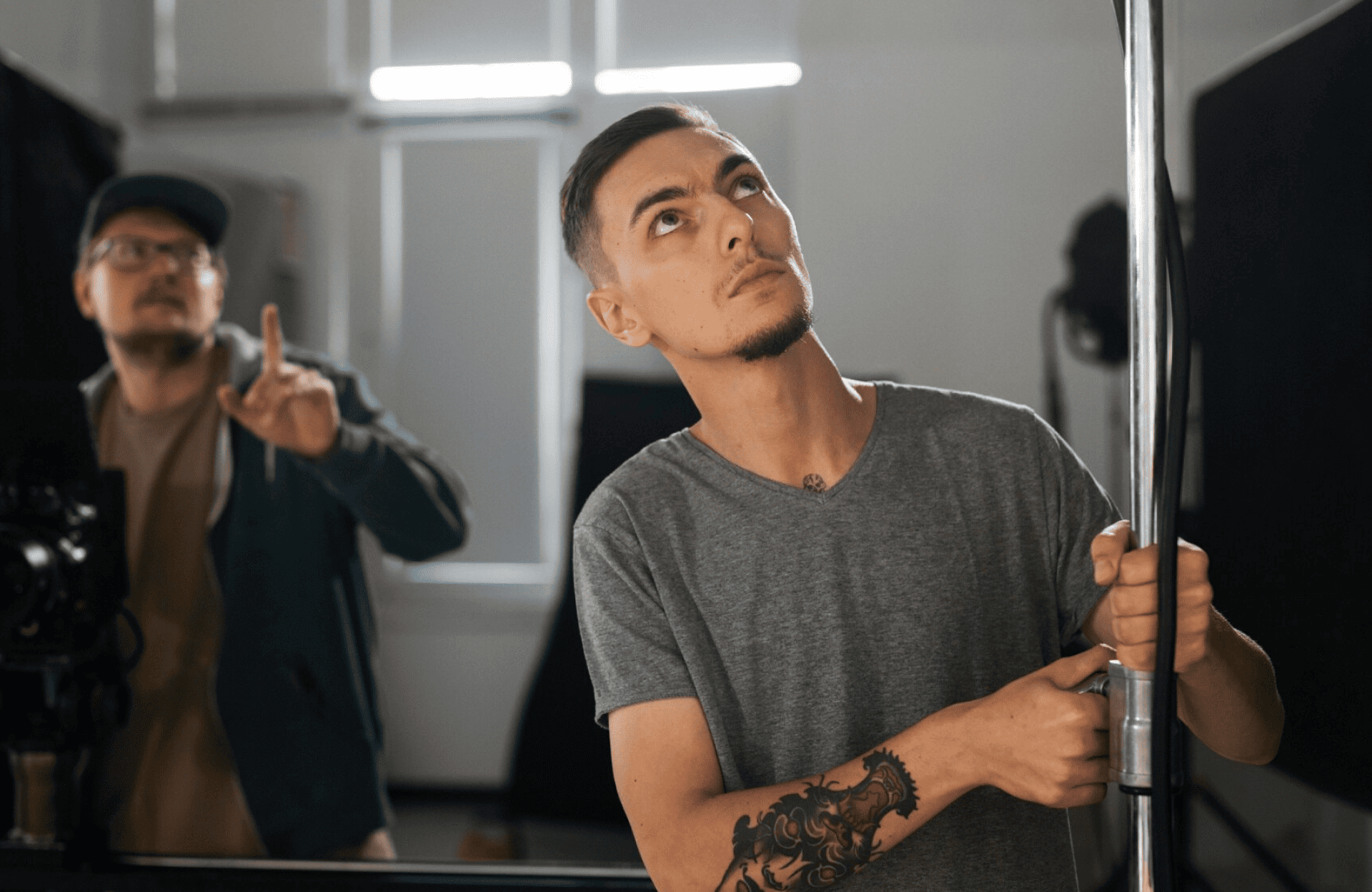FX Productions Canada Two men in a studio; one in the foreground adjusts a metal pole, while another near camera equipment gestures—capturing the behind-the-scenes energy of a Toronto Production Company like FX Productions Canada. Toronto Video Production Company