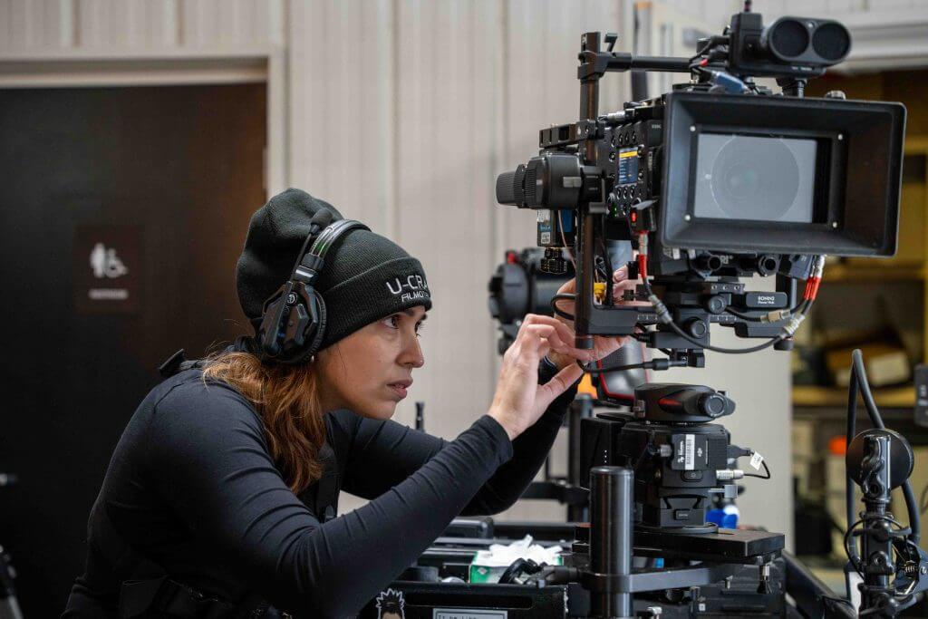FX Productions Canada A person wearing headphones and a beanie adjusts a professional video camera setup indoors, showcasing the expertise of Toronto Video Production, with equipment visible in the background. Toronto Video Production Company