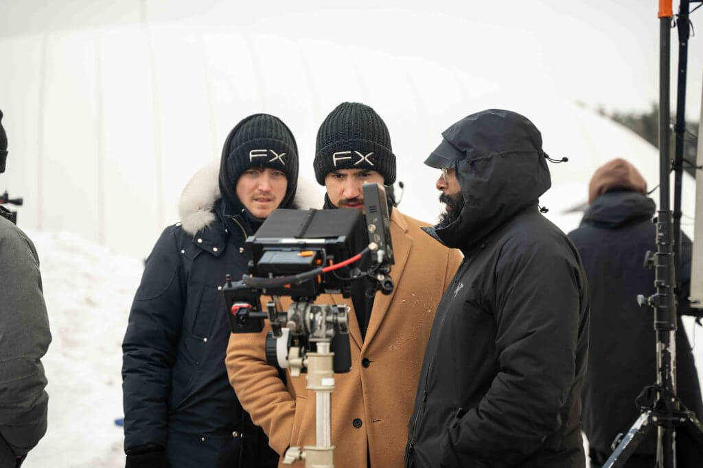 FX Productions Canada Three people in winter clothing stand outdoors around a camera monitor, viewing footage on a snowy film set with equipment in the background—capturing the action for FX Productions Canada, a leading Toronto Video Production company. Toronto Video Production Company
