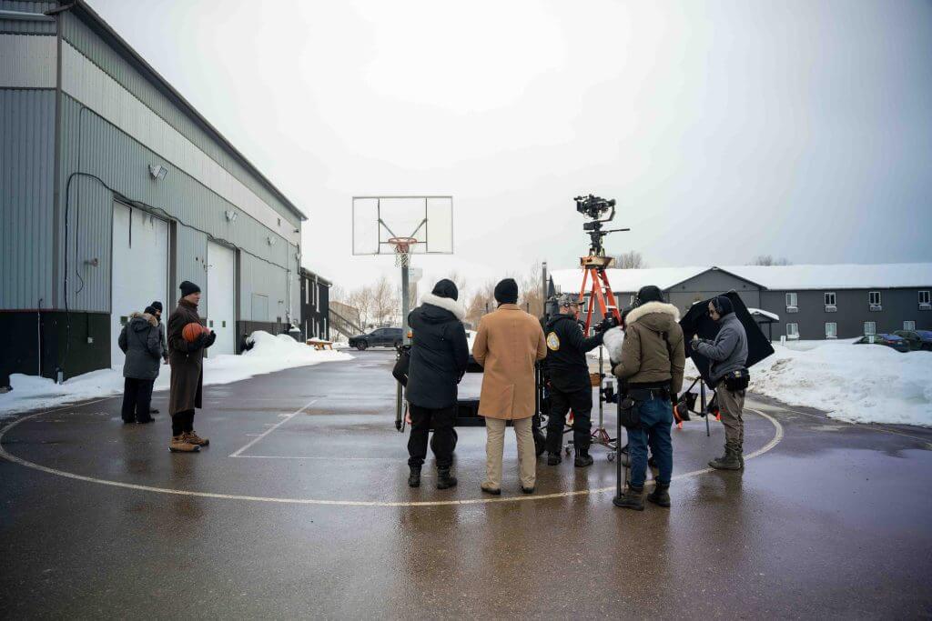 FX Productions Canada A film crew from FX Productions Canada sets up equipment on an outdoor basketball court in winter, with snow on the ground and several people wearing warm clothing. Toronto Video Production Company