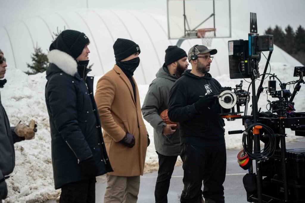 FX Productions Canada Four people in winter clothing stand outdoors by film equipment, with snow in the background and a basketball hoop visible, capturing a behind-the-scenes moment from an FX Productions Canada project. Toronto Video Production Company