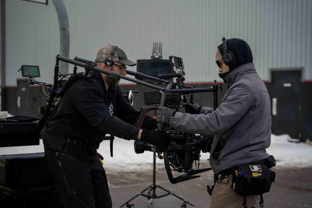 FX Productions Canada Two crew members from a Toronto Video Production team operate a professional camera rig outdoors, wearing headsets and winter clothing, with snow visible on the ground. Toronto Video Production Company