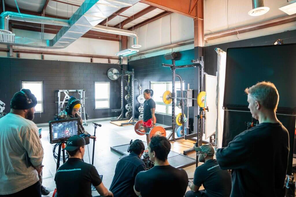FX Productions Canada A Toronto Video Production crew records a person lifting weights in a gym, using professional lighting and camera equipment set up for the shoot. Toronto Video Production Company