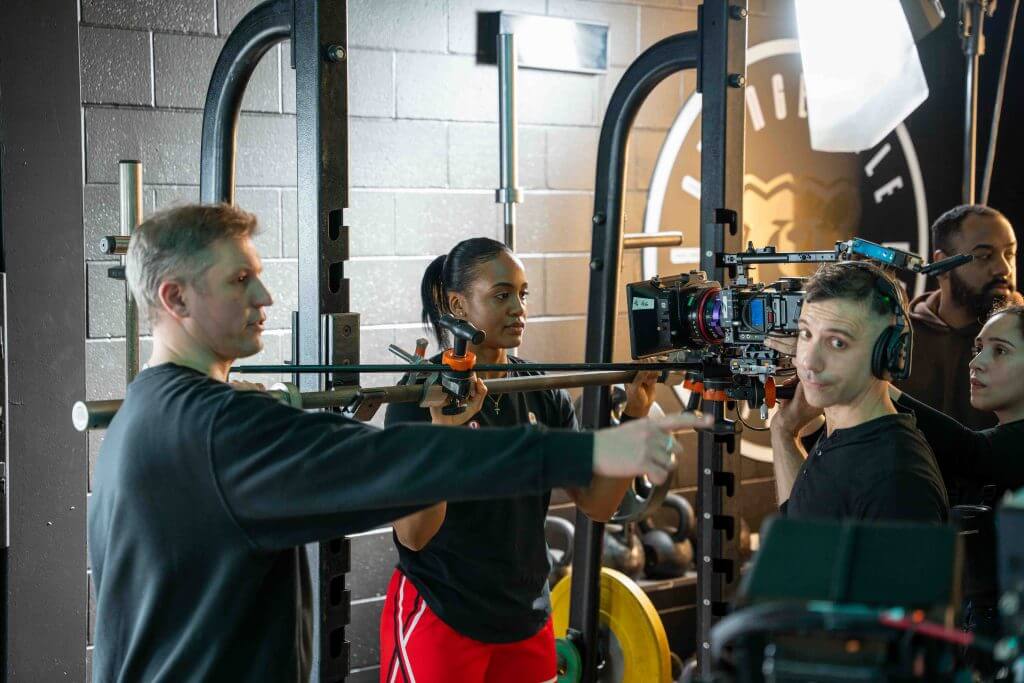 FX Productions Canada A film crew from a Toronto Video Production company sets up camera equipment in a gym, with one person pointing, another holding the rig, and two others observing. Toronto Video Production Company