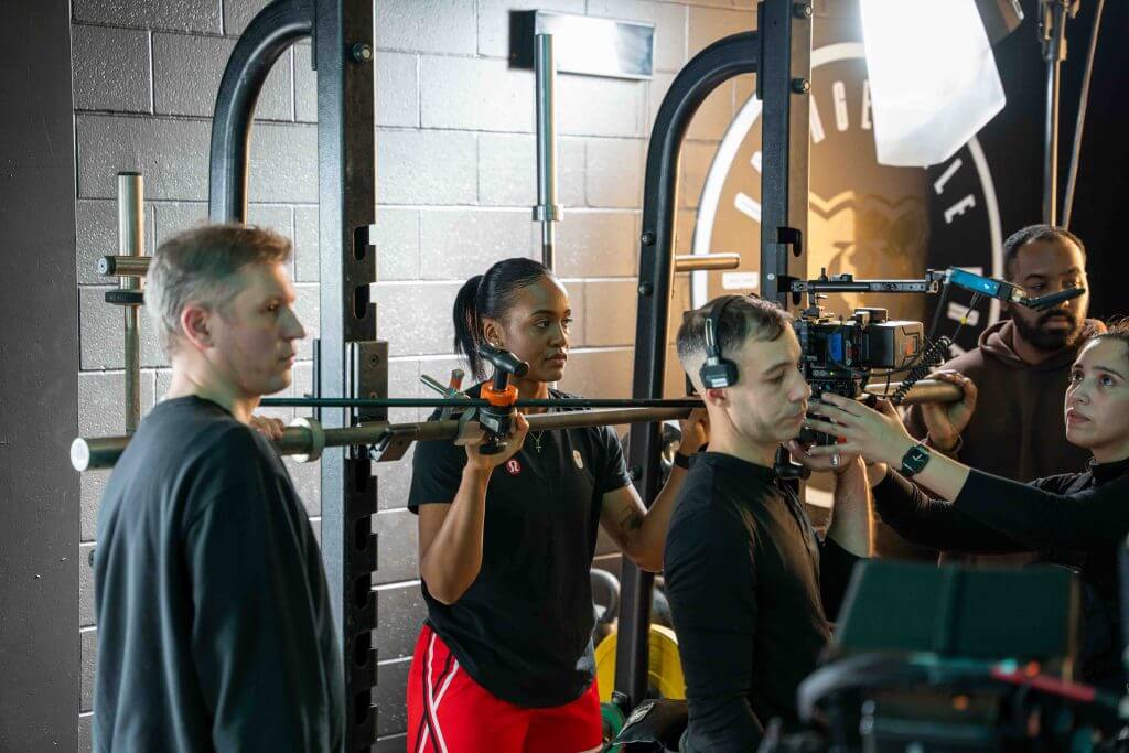 FX Productions Canada A Toronto Video Production crew sets up a camera shot in a gym, with several people adjusting equipment and wearing headsets, surrounded by filming gear. Toronto Video Production Company