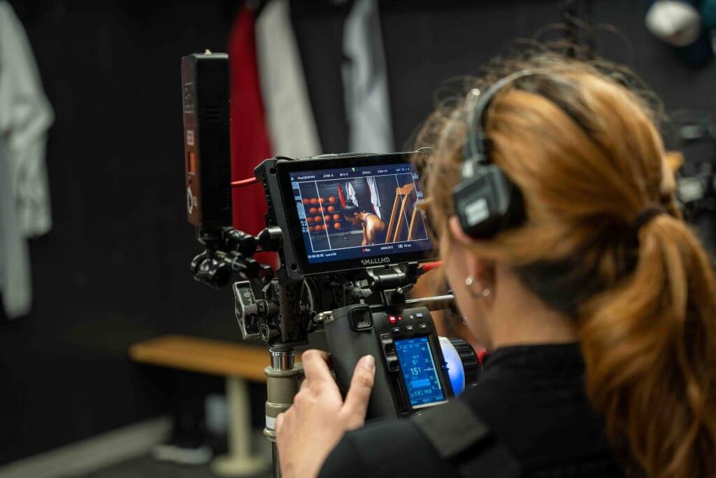 FX Productions Canada A person with headphones operates a professional video camera, focused on a monitor showing a scene being filmed indoors—capturing the creative process of a Toronto Video Production. Toronto Video Production Company