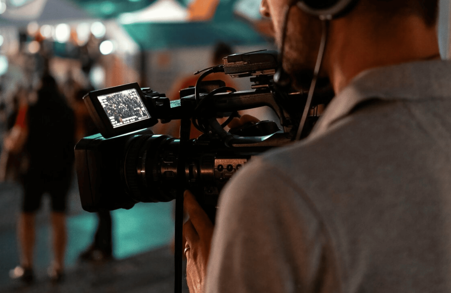 FX Productions Canada A person wearing headphones operates a professional video camera with a small screen, filming an event in an outdoor setting for FX Productions Canada. Toronto Video Production Company