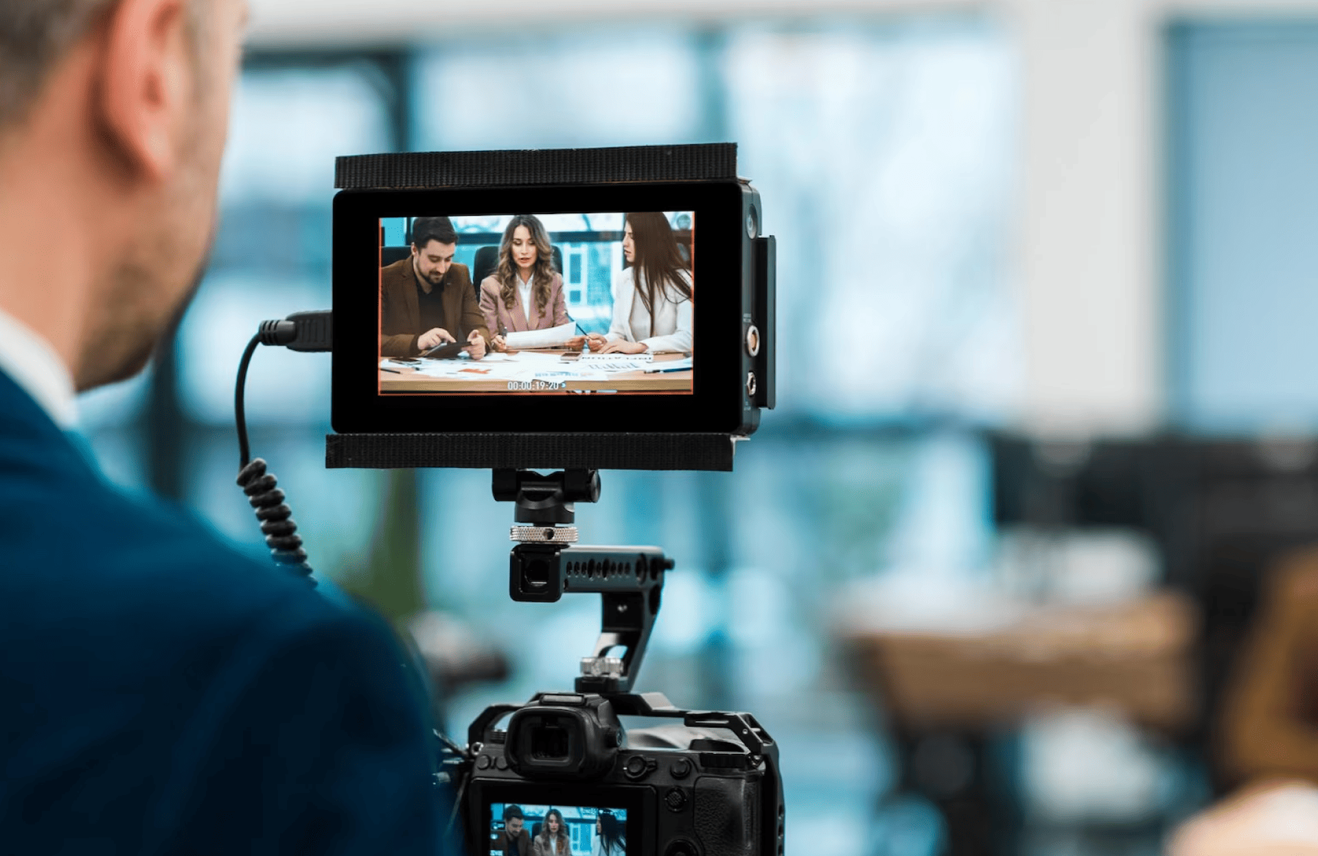 FX Productions Canada A person films a group of people working at a table, as shown on the camera’s display screen in an indoor setting. Toronto Video Production Company