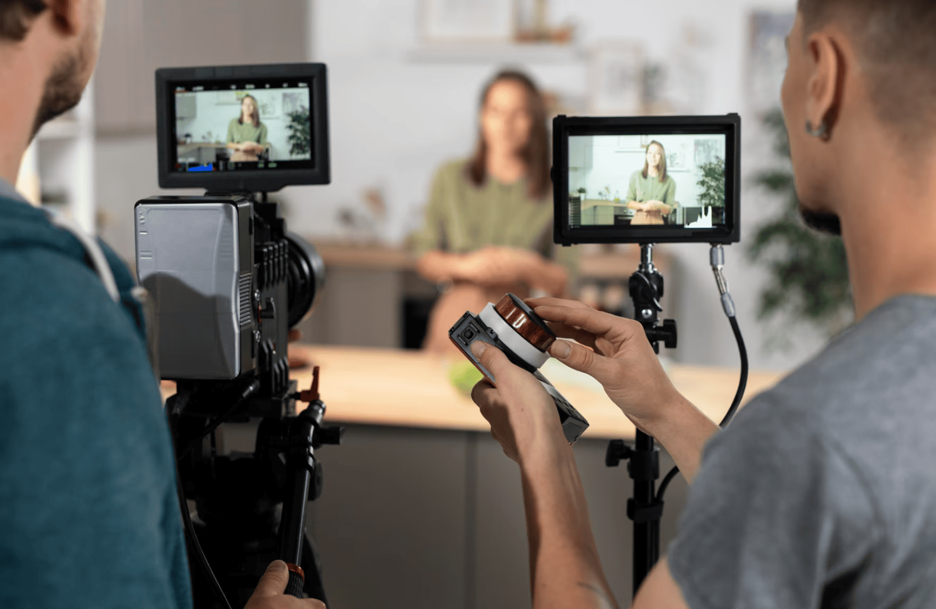 FX Productions Canada Two crew members operate cameras and monitors while filming a person sitting at a table in a studio setting. Toronto Video Production Company