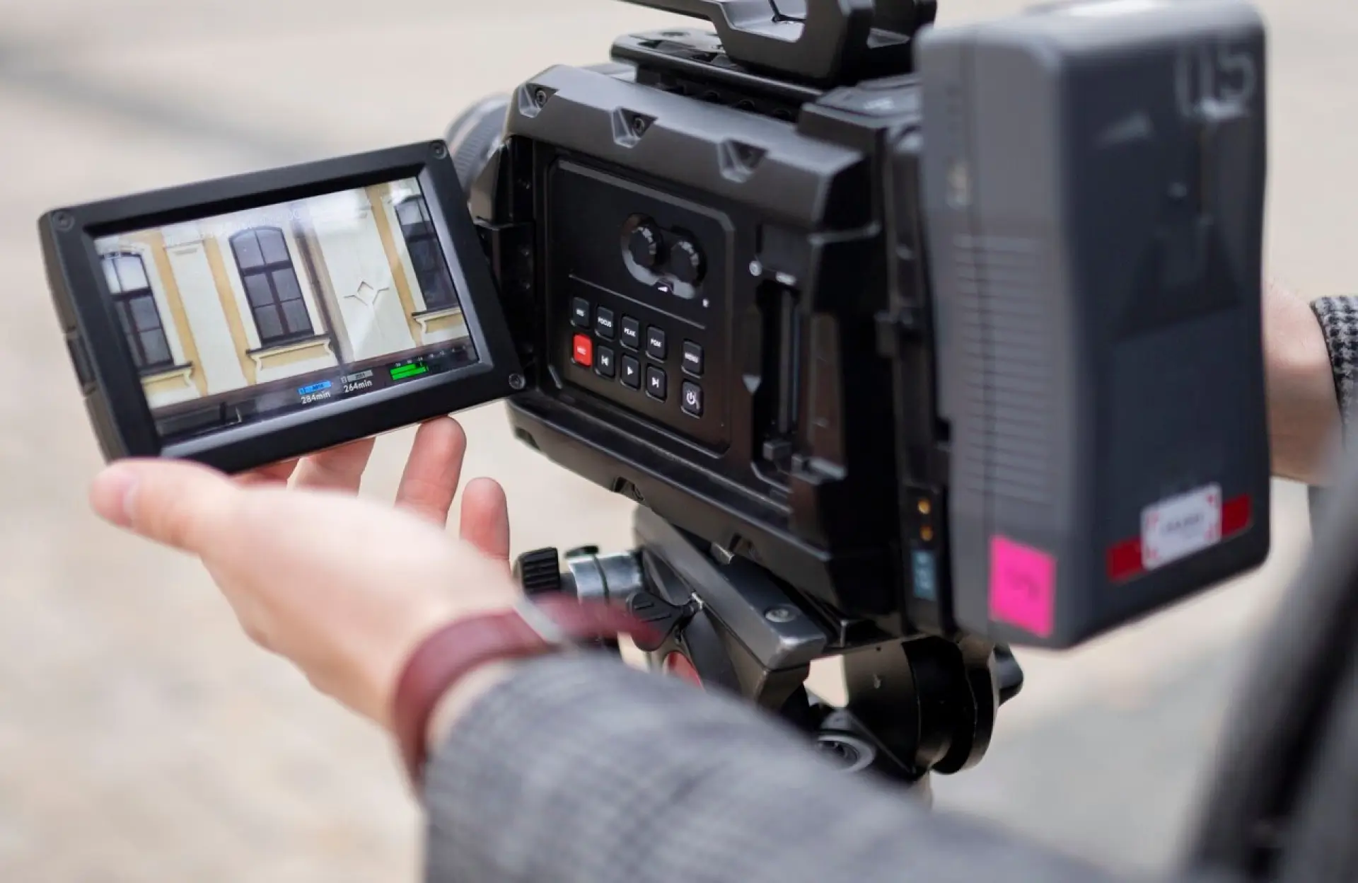 FX Productions Canada A person operates a professional video camera, adjusting settings while the screen displays a building’s exterior with windows. Toronto Video Production Company