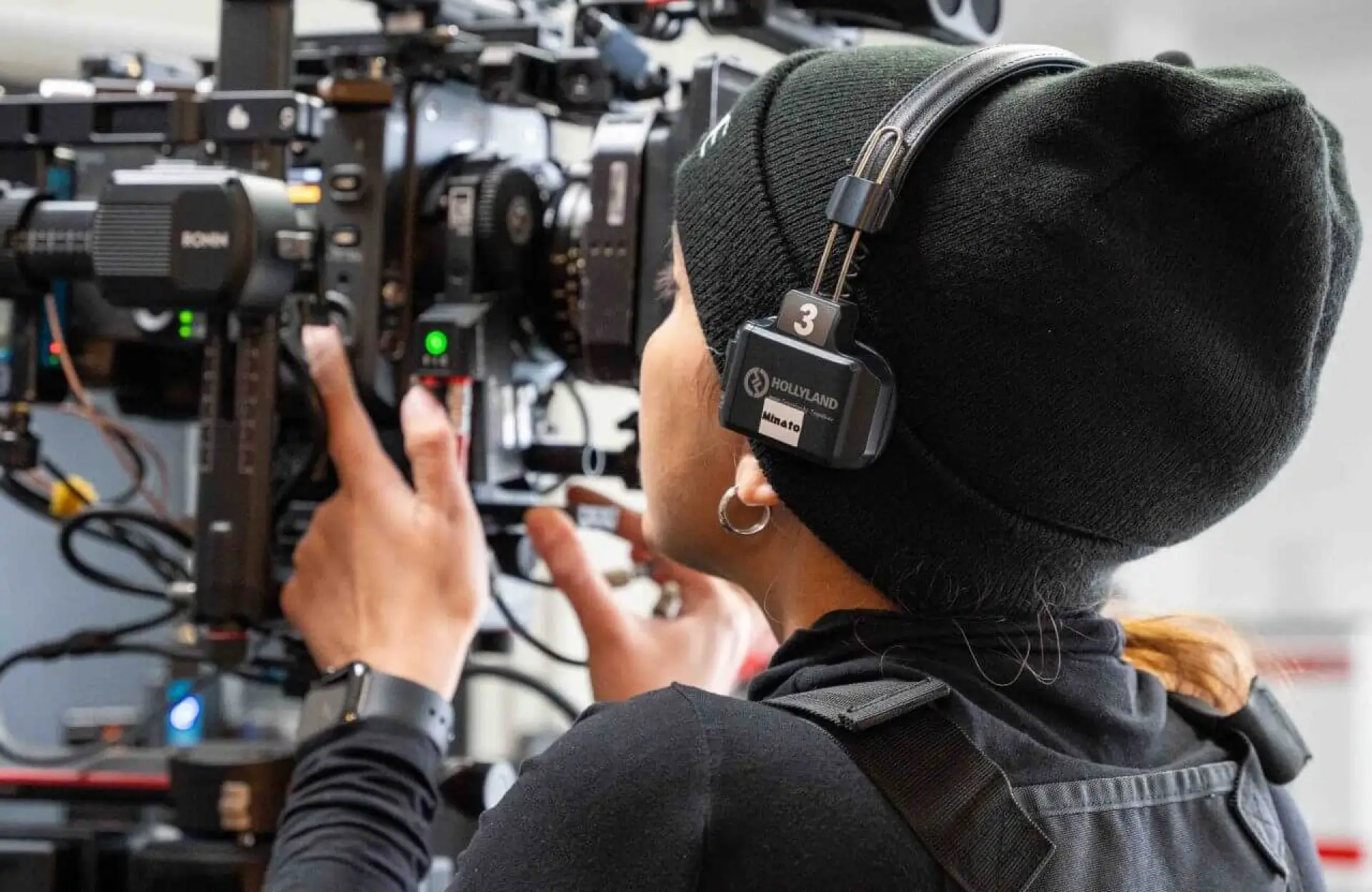 FX Productions Canada Person wearing a headset and black beanie operates a professional video camera, adjusting controls and focusing on the viewfinder. Toronto Video Production Company