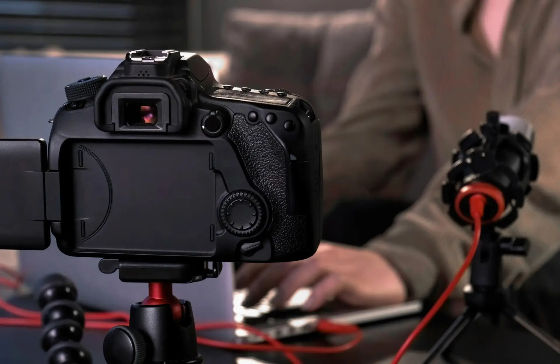 FX Productions Canada A DSLR camera on a tripod is pointed at a person typing on a laptop, with a microphone and cables visible on the table. Toronto Video Production Company