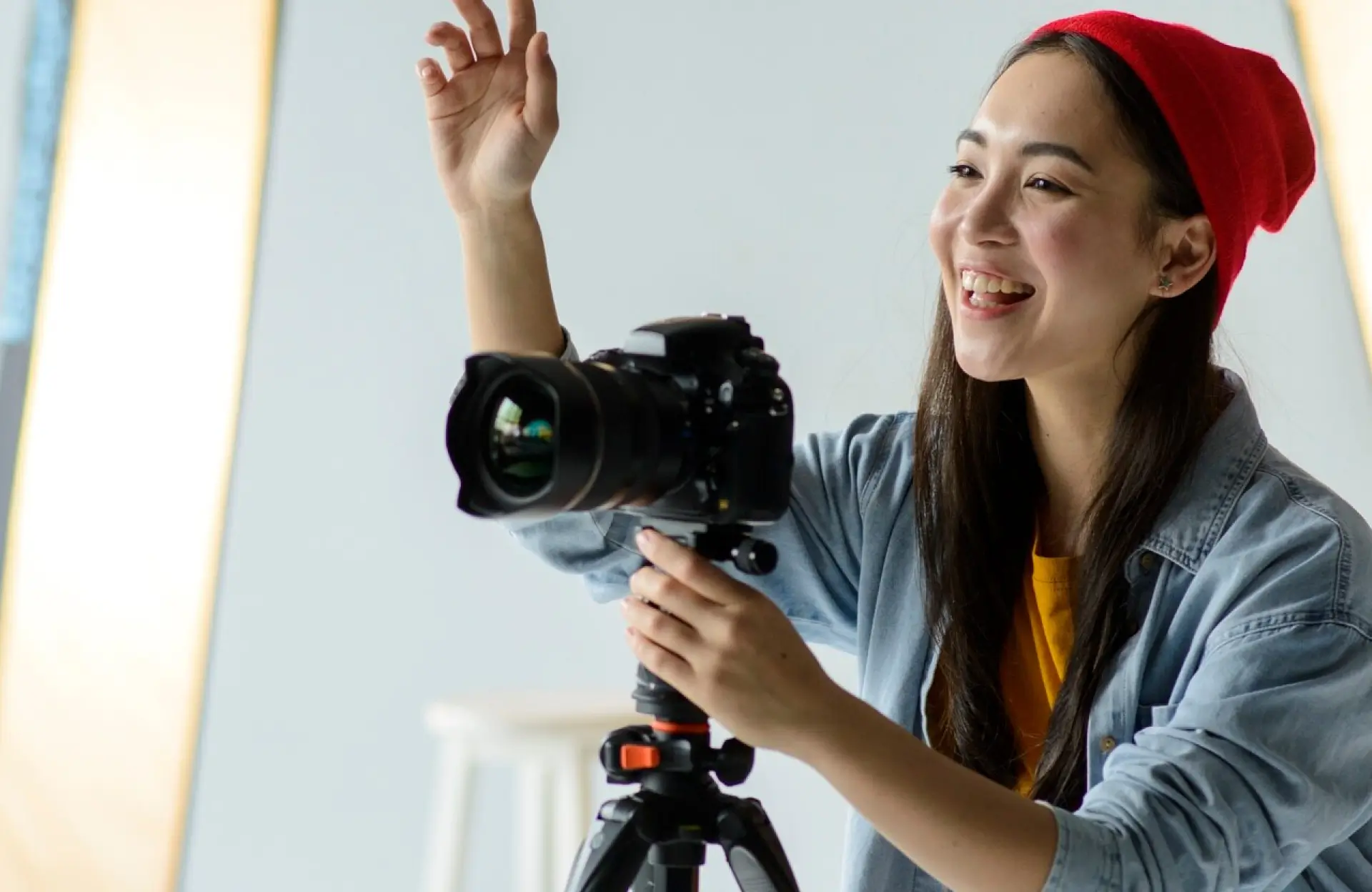 FX Productions Canada A person wearing a red beanie smiles while adjusting a camera mounted on a tripod in a well-lit indoor space. Toronto Video Production Company