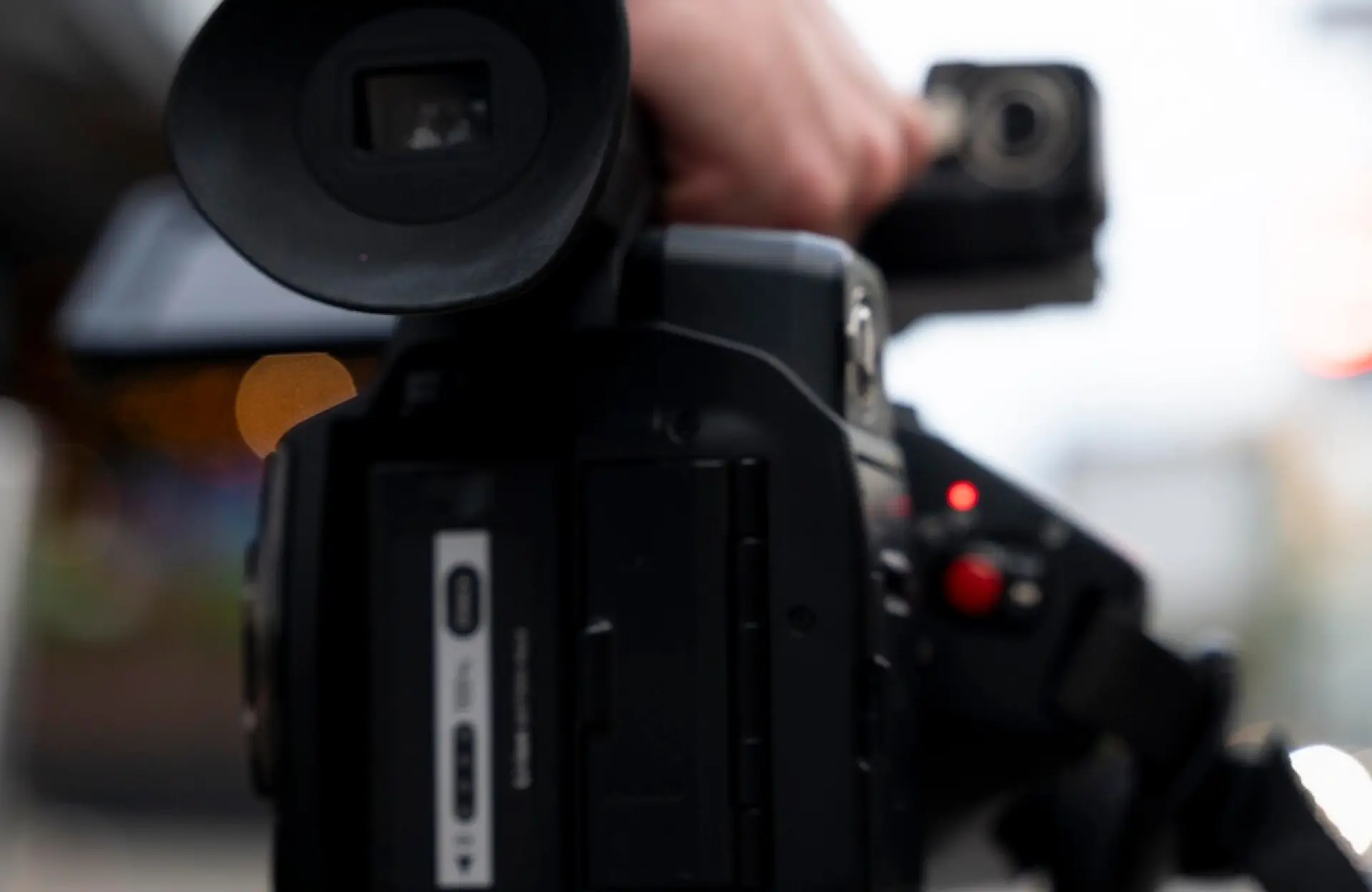 FX Productions Canada Close-up view of a person operating a professional video camera, with the camera lens and controls in focus. Toronto Video Production Company