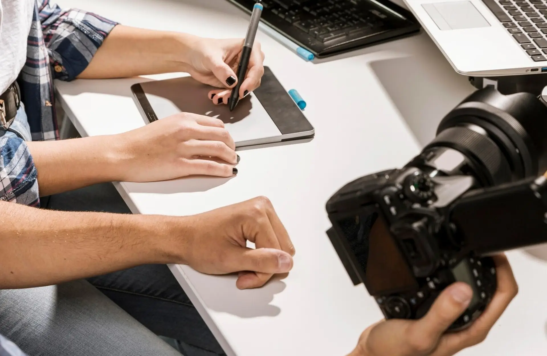 FX Productions Canada Person using a digital drawing tablet with a stylus next to a camera and another person’s arm on a white desk. Toronto Video Production Company