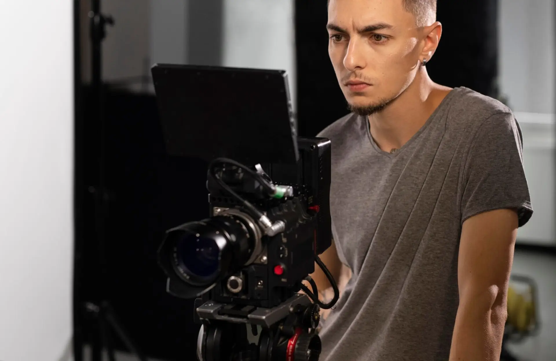 FX Productions Canada A person with short hair and a gray t-shirt operates a professional video camera, focusing on a monitor in a studio setting. Toronto Video Production Company