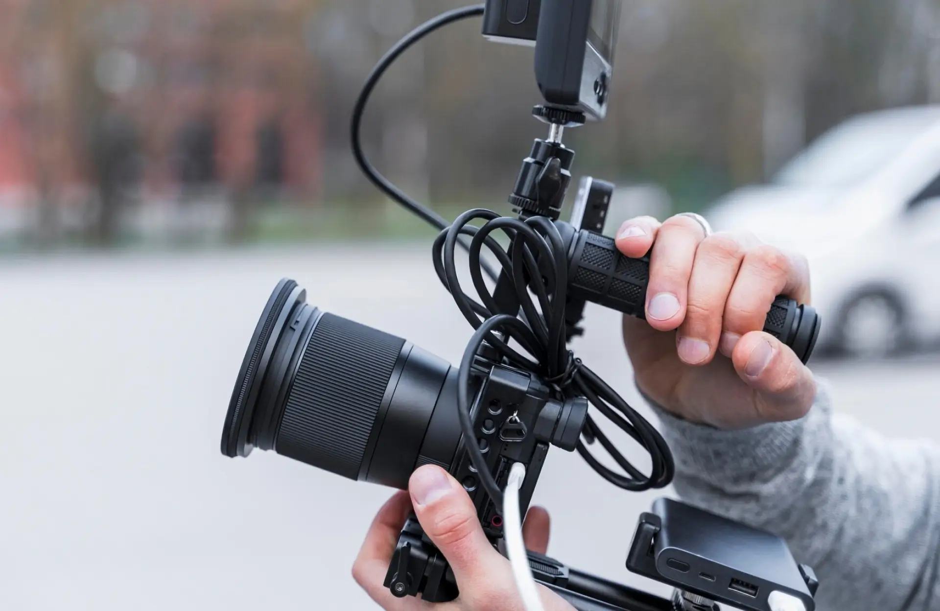 FX Productions Canada A person holding a professional digital video camera with attached monitor and cables, preparing to film outdoors. Toronto Video Production Company