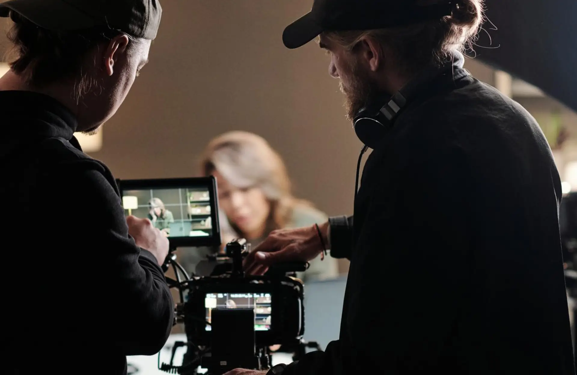 FX Productions Canada Two crew members operate a professional video camera and monitor, filming a woman who is out of focus in the background. Toronto Video Production Company