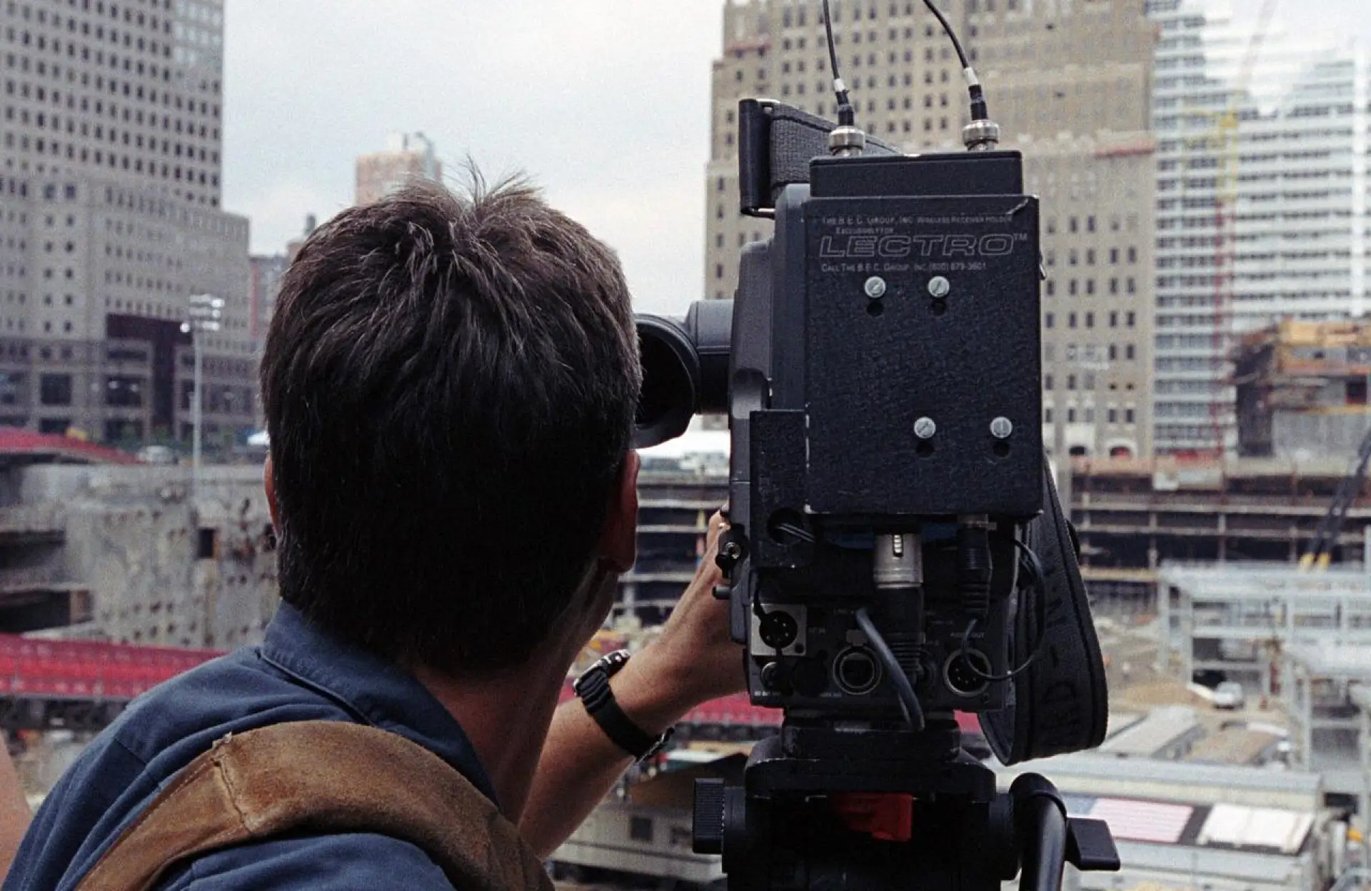 FX Productions Canada A person operates a professional video camera on a tripod, filming a construction site in an urban area with tall buildings in the background. Toronto Video Production Company
