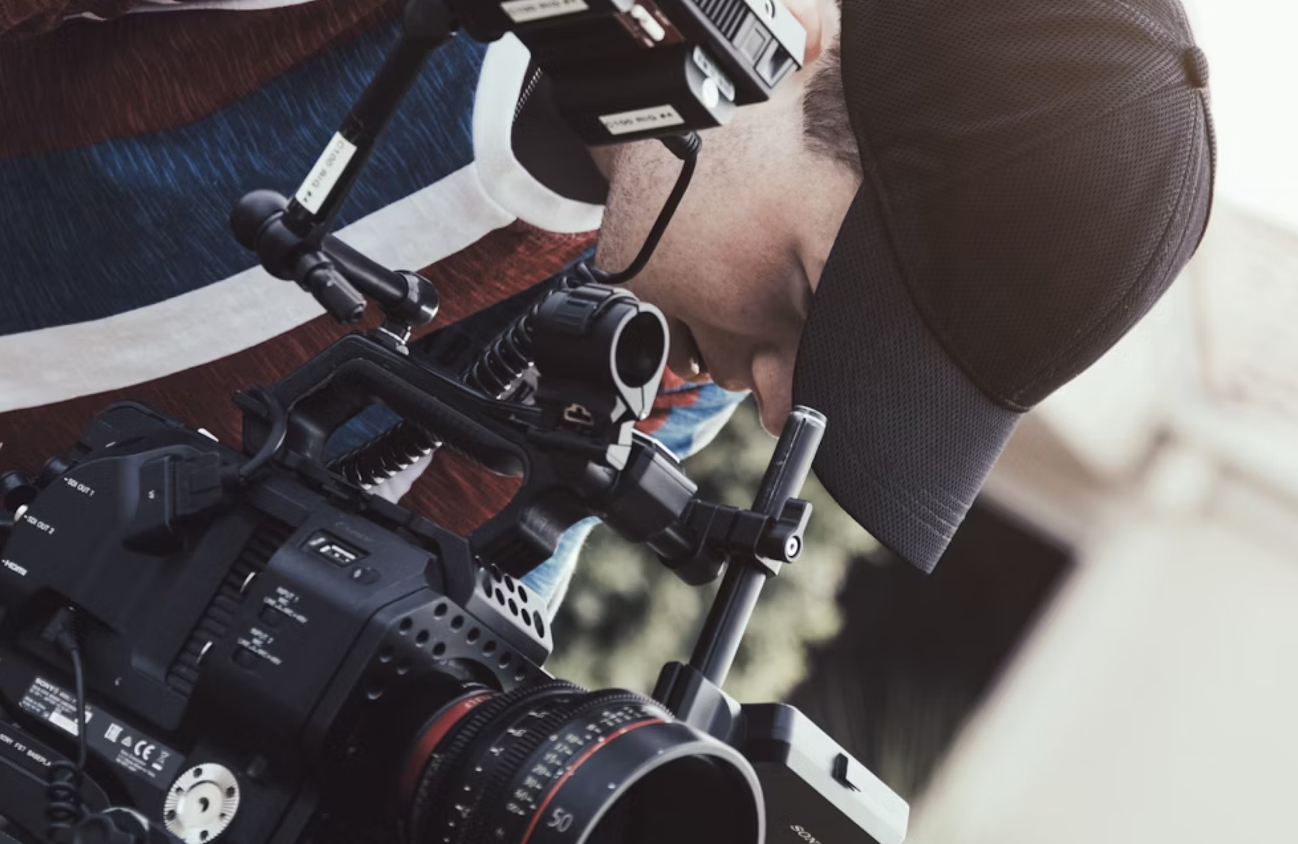 FX Productions Canada A person wearing a black cap operates a professional video camera, focusing intently on the equipment—capturing dynamic content for a leading video production company Toronto. Toronto Video Production Company