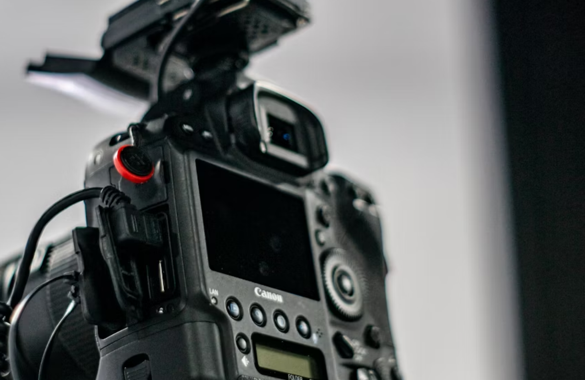 FX Productions Canada Close-up view of the back of a Canon digital camera, showing buttons, dials, and screen, with an external accessory mounted on top. Toronto Video Production Company