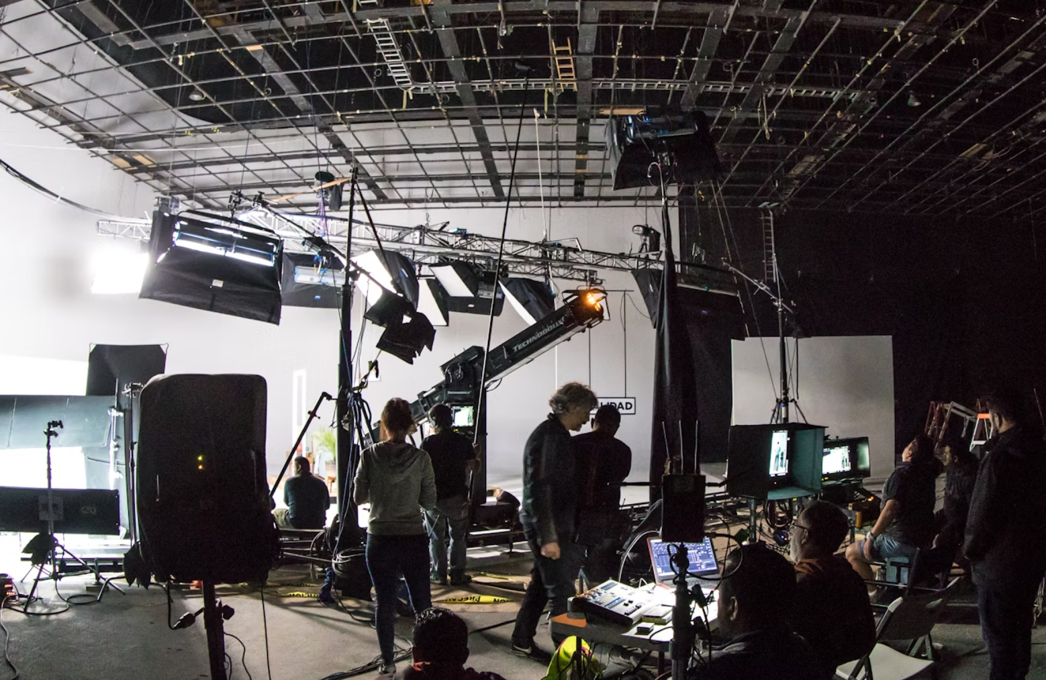 FX Productions Canada Film crew working on a set with lighting equipment, cameras, monitors, and crew members in a large indoor studio environment. Toronto Video Production Company