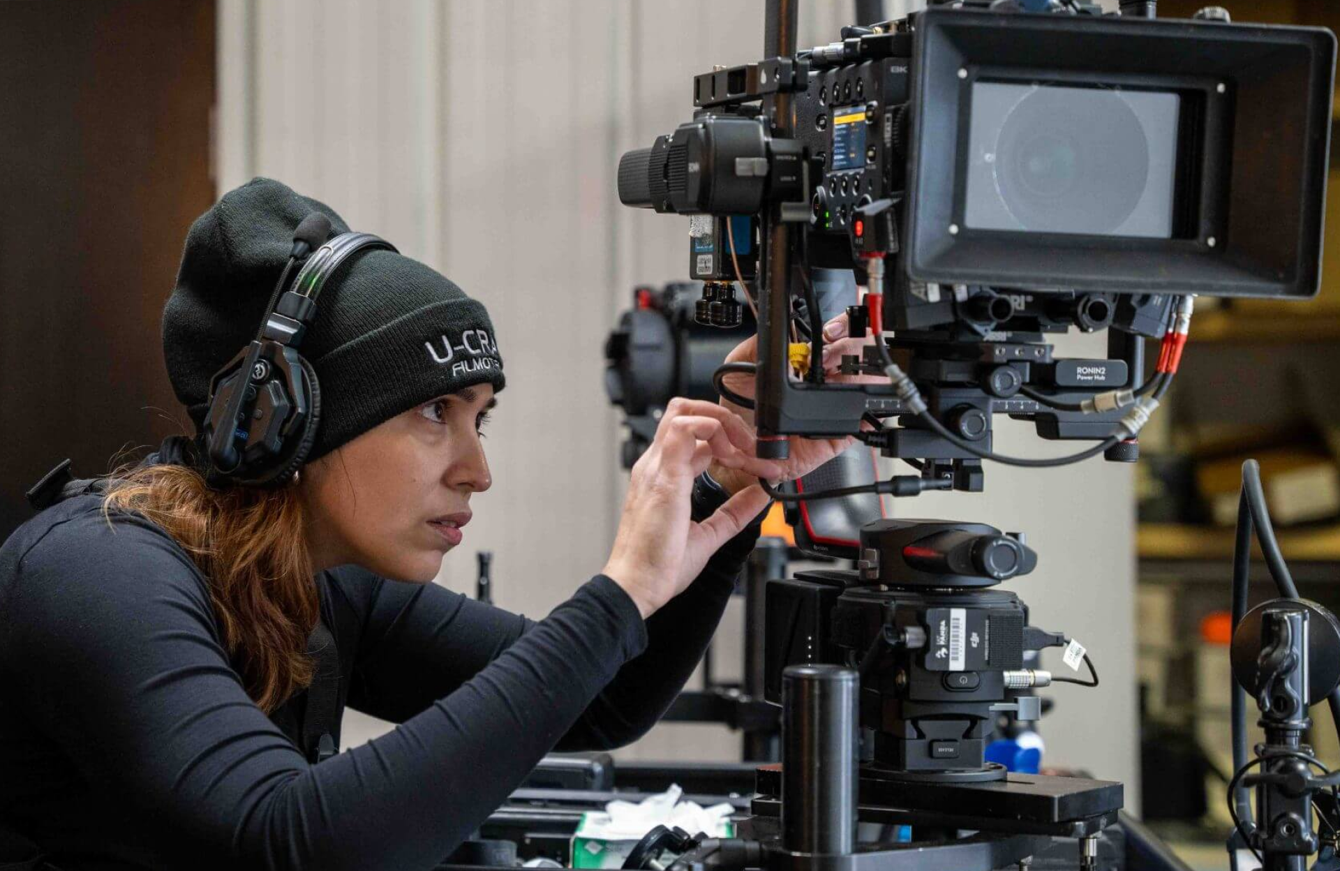 FX Productions Canada A person wearing headphones and a beanie adjusts a professional video camera rig indoors, showcasing the expertise found at top video production companies Toronto. Toronto Video Production Company