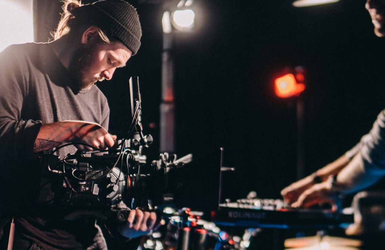 FX Productions Canada A person in a beanie operates a professional video camera on a dimly lit set, while another adjusts audio equipment nearby. Toronto Video Production Company