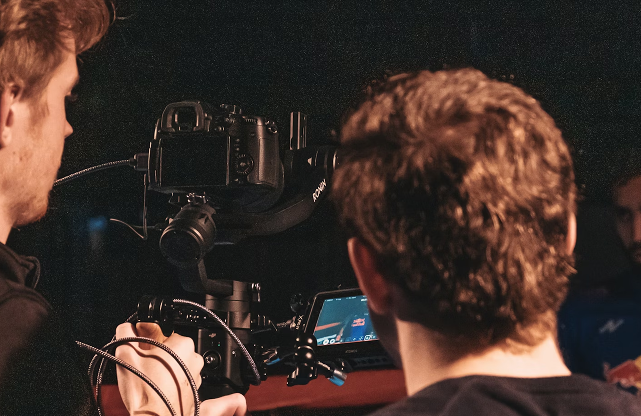 FX Productions Canada Two people operating a professional camera rig with a monitor, focusing on filming or recording in a dimly lit setting. Toronto Video Production Company