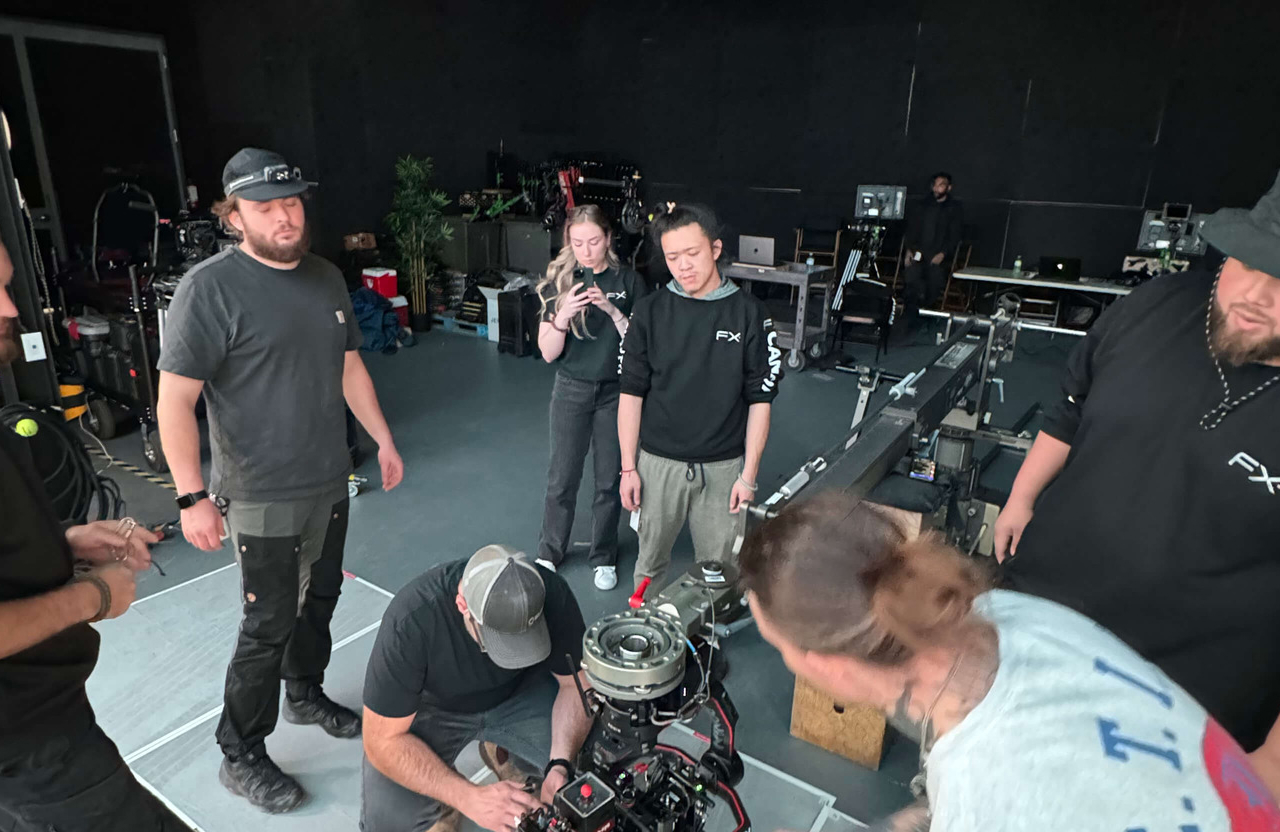 FX Productions Canada A group of people in a studio examine camera equipment, with some standing and others crouched near the camera on a track. Toronto Video Production Company