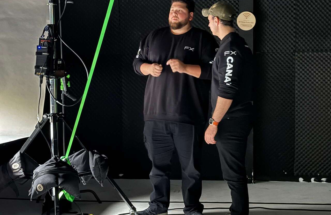 FX Productions Canada Two men in black FX CANADA shirts stand and talk next to studio equipment and lighting inside a soundproofed room. Toronto Video Production Company