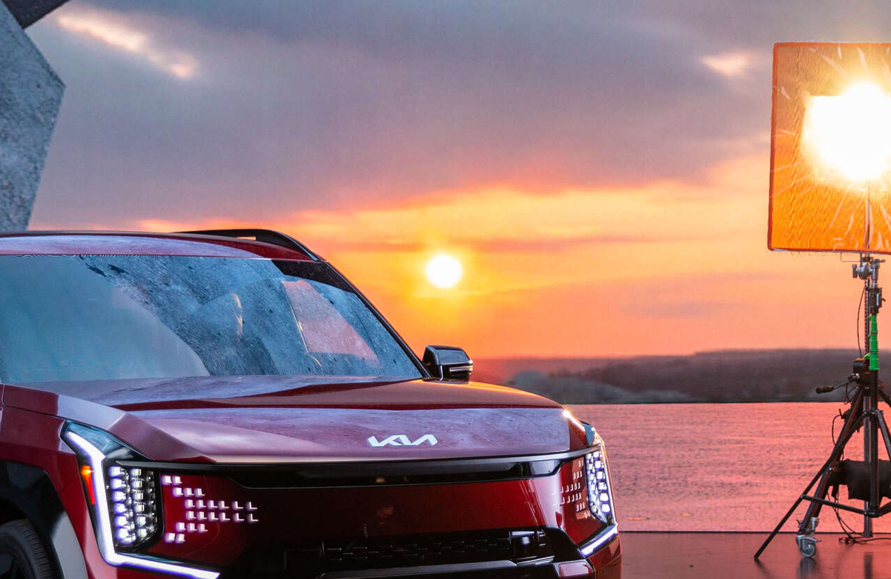 FX Productions Canada A red Kia SUV parked near water at sunset, with studio lights and equipment visible on the right side of the image. Toronto Video Production Company