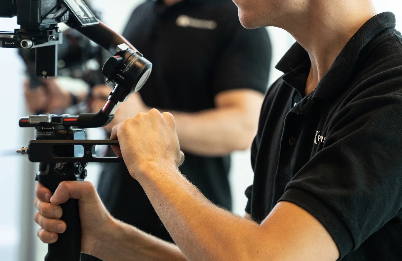 FX Productions Canada Person in a black polo shirt adjusts a mounted camera stabilizer while another stands in the background, both exemplifying professional Toronto video production services. Toronto Video Production Company