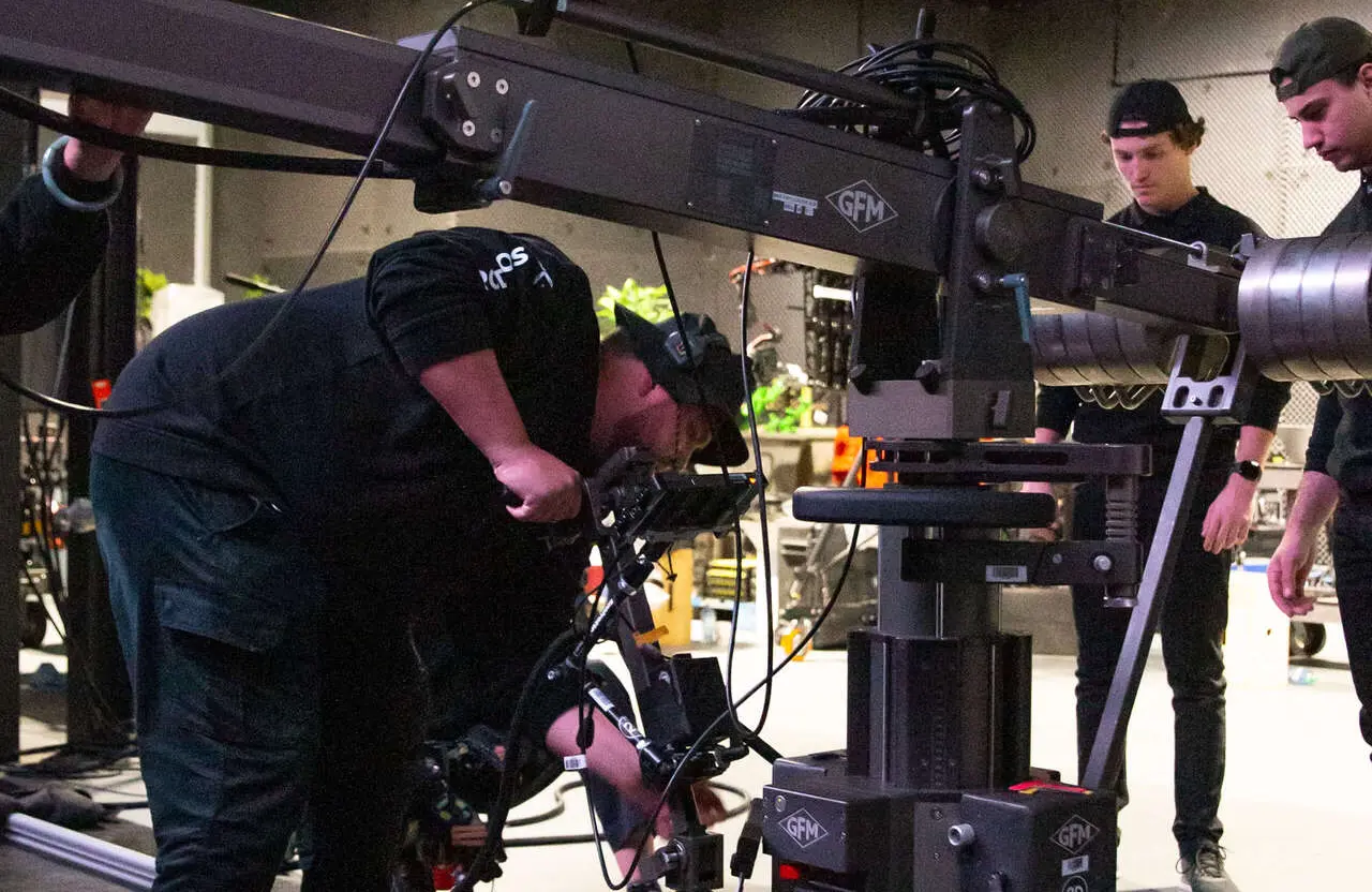 FX Productions Canada Several crew members adjust camera equipment on a large film set in Toronto, preparing lighting, rigging, and production gear for a sales enablement video. Toronto Video Production Company