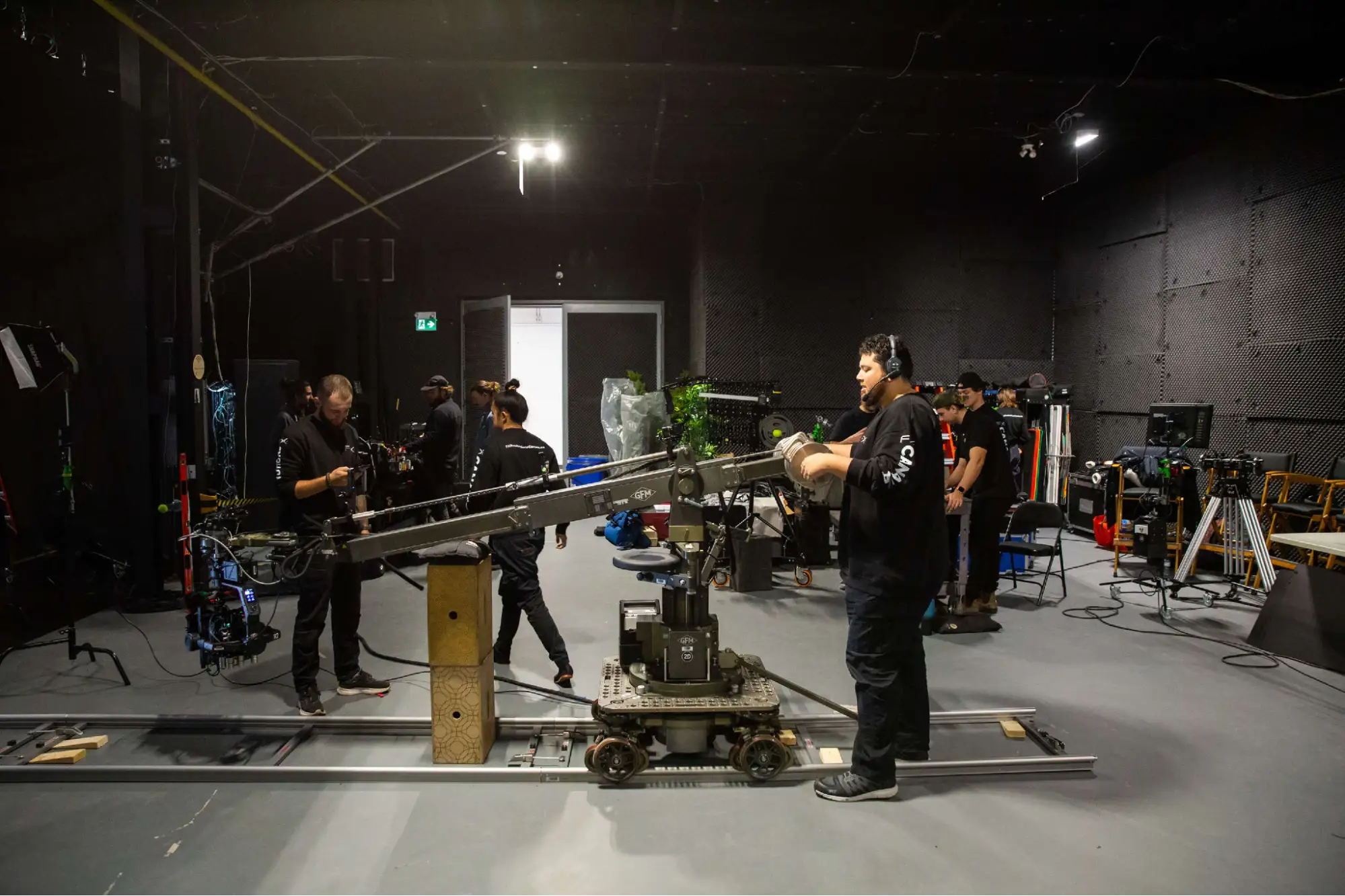 FX Productions Canada Film crew operating a camera crane on tracks in a studio with various equipment and lighting setups visible in the background. Toronto Video Production Company
