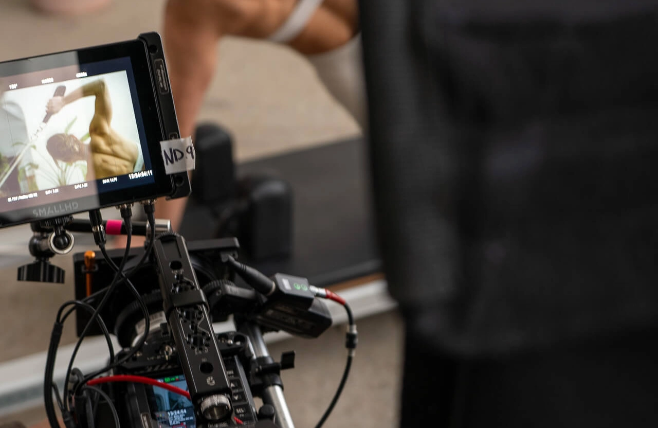 FX Productions Canada A close-up of a video camera setup filming a person exercising, with the subject's image displayed on the camera monitor—showcasing expert skills often seen in automotive video production Toronto. Toronto Video Production Company