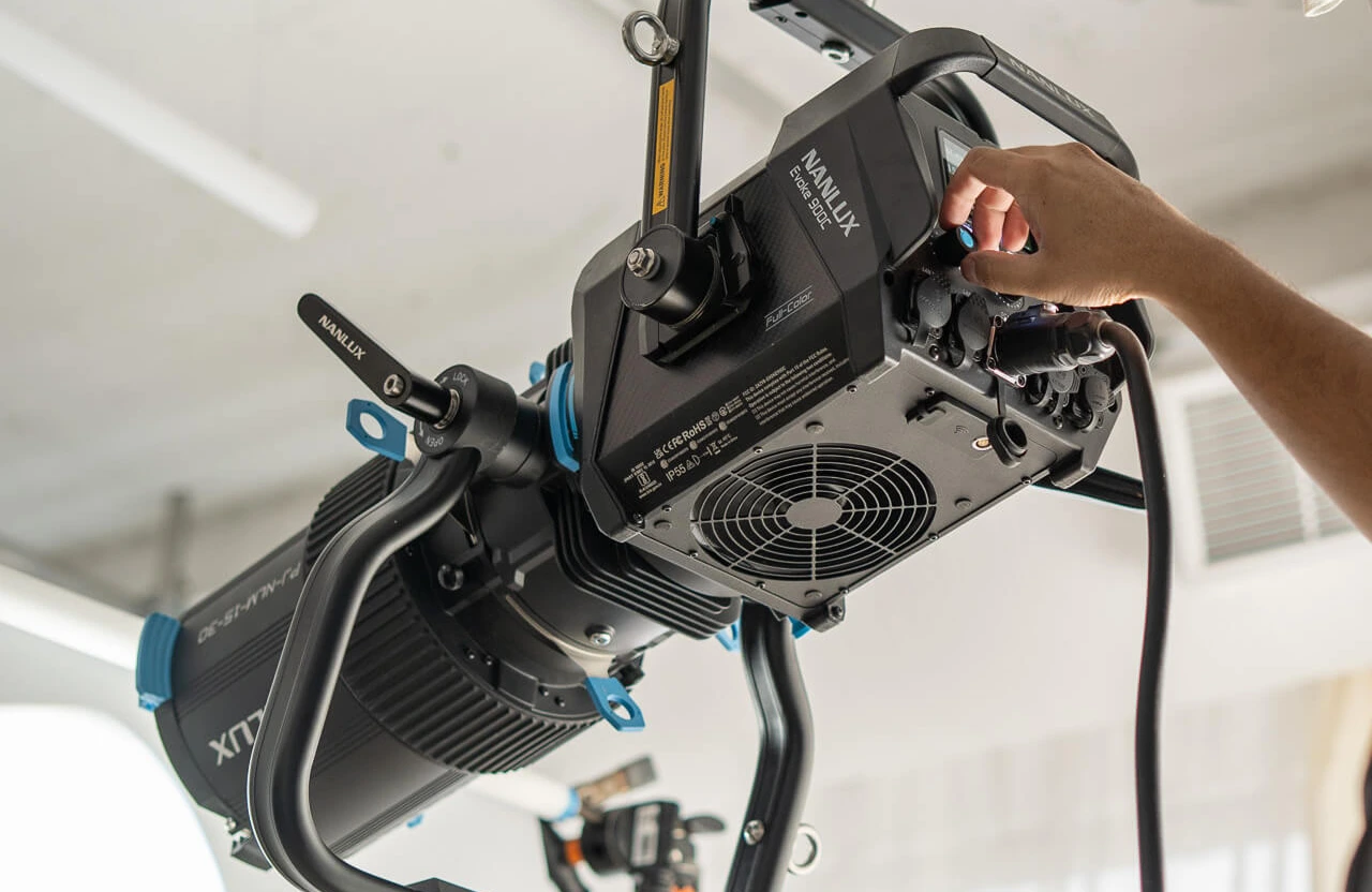 FX Productions Canada A person adjusts the controls on a professional studio light fixture mounted on a stand in an indoor setting at a video production company Toronto. Toronto Video Production Company