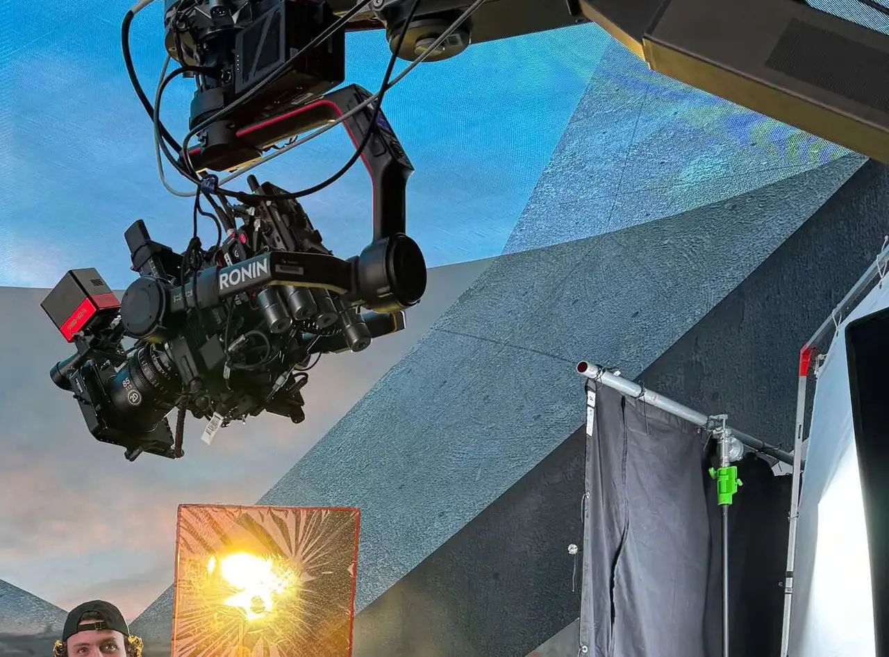 FX Productions Canada A large camera rig is suspended on set, aimed at a lit reflective surface, with abstract geometric backgrounds and filmmaking equipment visible. Toronto Video Production Company