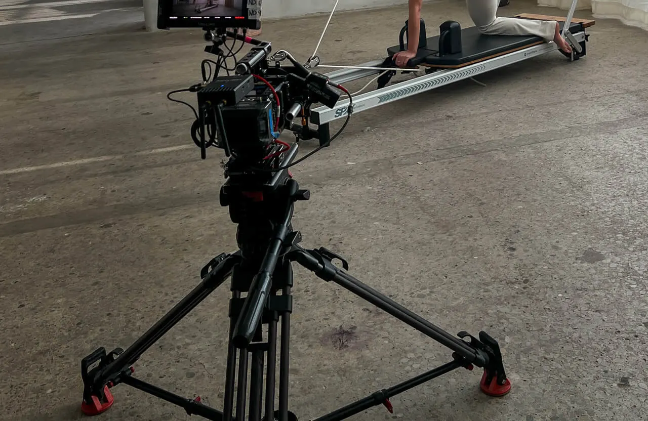 FX Productions Canada A professional video camera on a tripod films a person sitting in a rowing shell indoors on a concrete surface, capturing dynamic scenes for food and beverage commercial production Toronto. Toronto Video Production Company